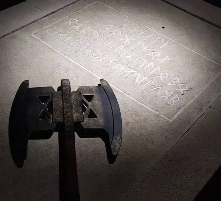 Inscripción de piedra con un hacha de hierro posada sobre ella