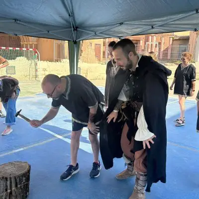 Persona medieval formando a un compañero para hacer una construcción de madera